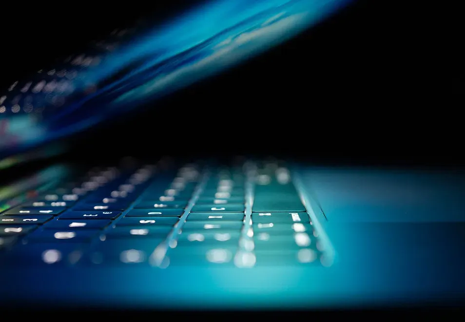 Illuminated laptop keyboard in a dark room representing vigilant security monitoring